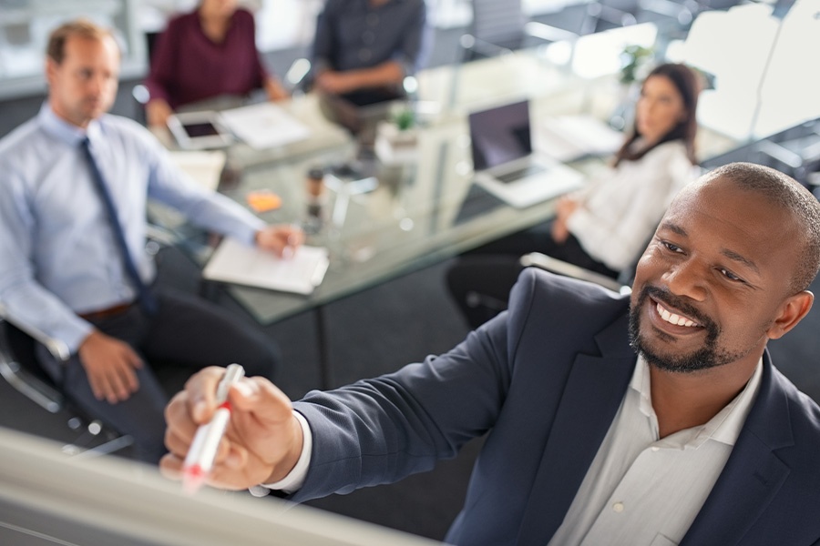 Business Insurance - Businessman Brainstorming and Writing on a Whiteboard During a Team Member Meeting in the Insurance Office