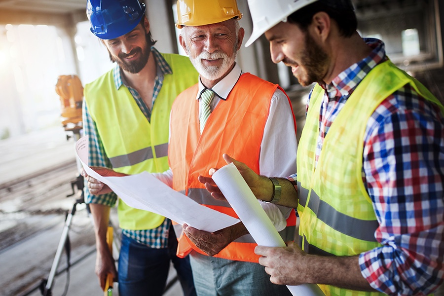 Specialized Business Insurance - Engineers and Construction Site Manager Conversing and Dealing with Blueprints and Construction Plans